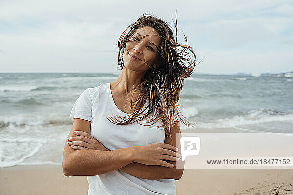 Smiling woman with arms crossed at beach