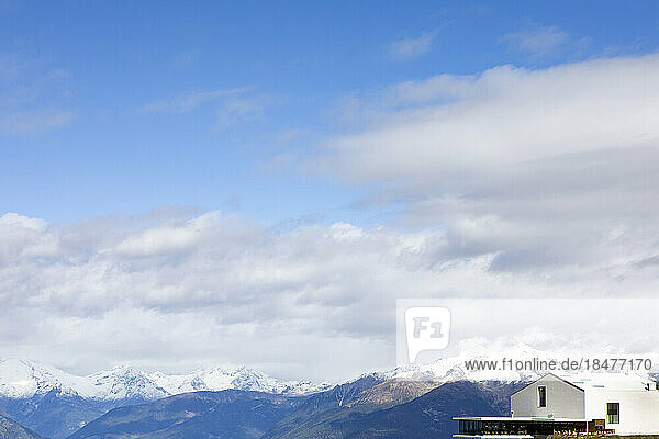 Art museum near snowcapped mountains under clouds on sunny day