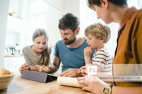 Father sharing tablet PC with son and daughter at home