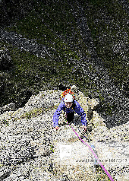 Woman climbing rock on mountain Pillar  Western Fells  Lake District  England