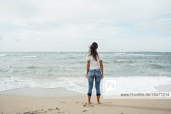 Woman standing near shore and looking at sea