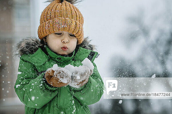 Boy blowing snow having fun in winter