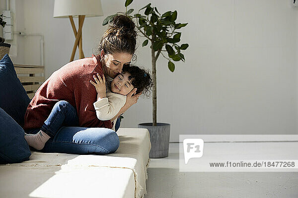 Mother and daughter hugging on sofa
