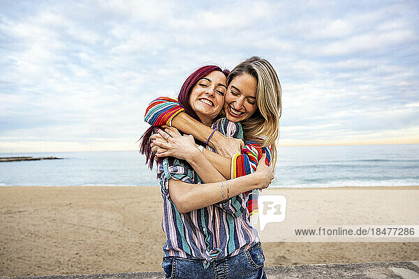Happy woman hugging friend from behind at beach