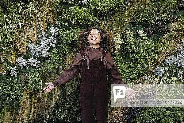 Happy woman wearing bib overalls in front of plants