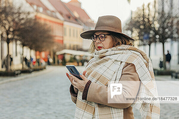 Senior woman using smart phone standing on street