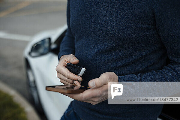 Man with car key using mobile phone