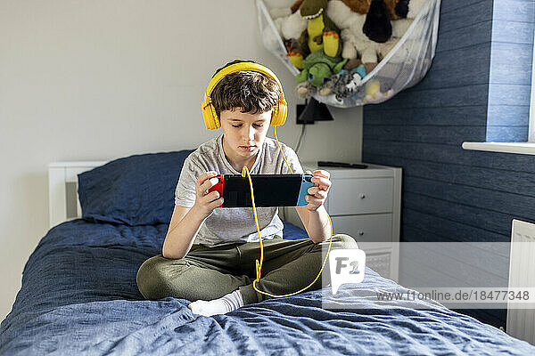 Boy wearing headphones playing video game on tablet PC