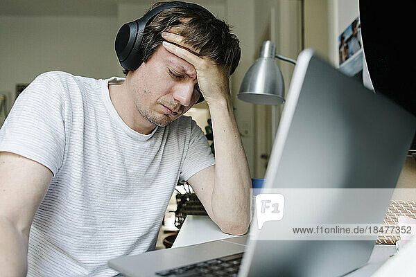 Freelancer with head in hand sitting in front of laptop