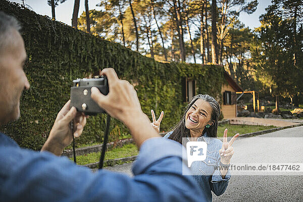 Mature man taking picture of happy woman on the road