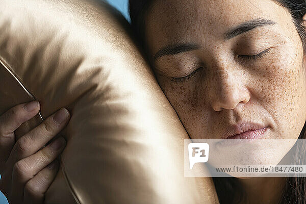 Woman with eyes closed sleeping on silk pillow