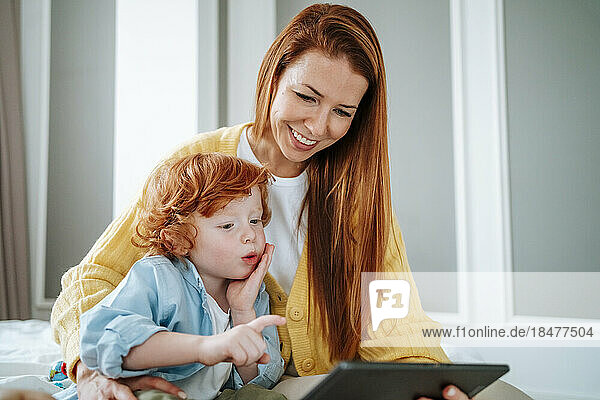 Smiling mother sharing tablet PC with son at home