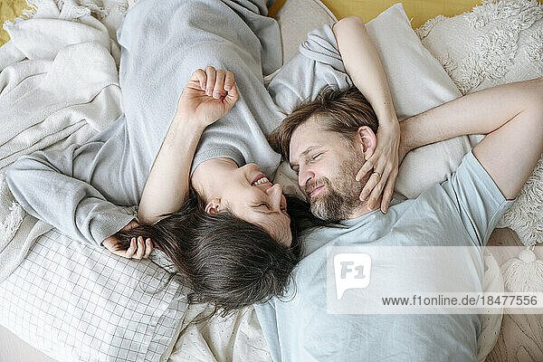 Smiling couple lying together on cushions at home