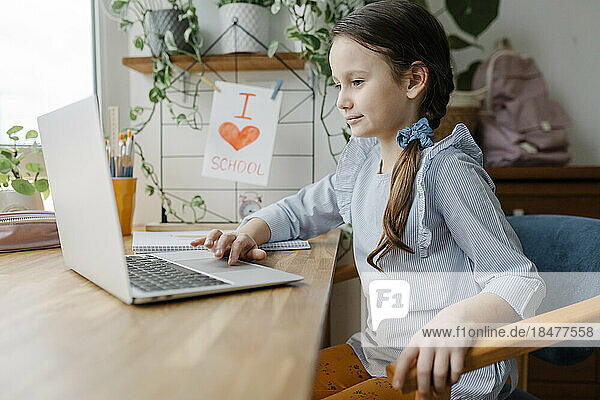 Smiling girl using laptop at home