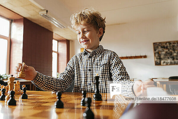 Lächelnder Junge  der Spaß beim Spielen im Schachclub hat