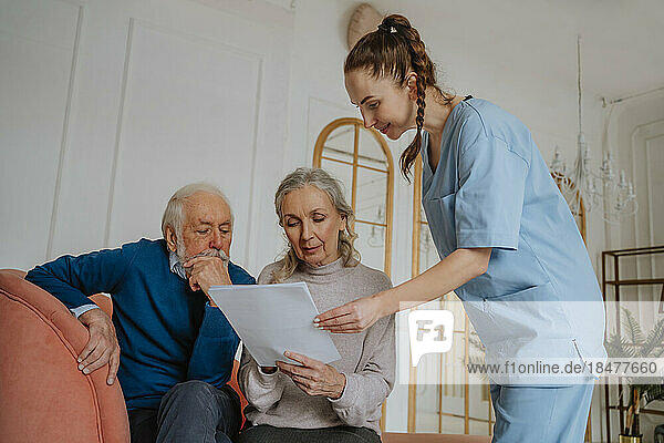 Senior patients signing report by smiling caregiver at home