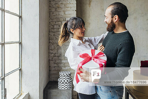 Happy couple with gift standing at home