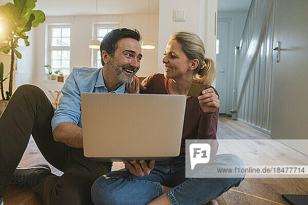 Happy couple with laptop and credit card sitting at home