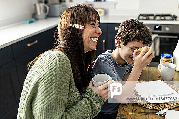 Glückliche Frau genießt und frühstückt mit ihrem Sohn zu Hause