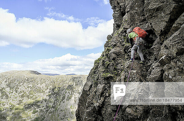 Man wearing backpack climbing on mountain  Lake District  England