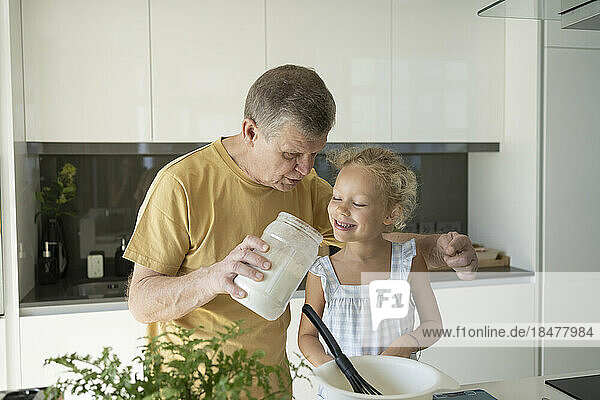 Grandfather and granddaughter baking together in kitchen at home