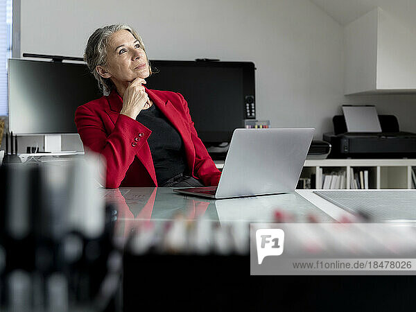 Nachdenkliche ältere Geschäftsfrau sitzt am Schreibtisch im Büro