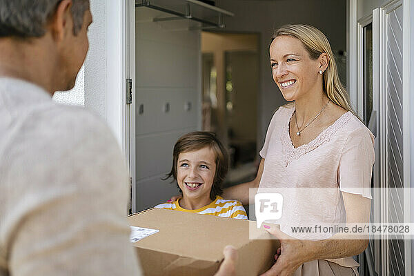 Happy woman with son receiving parcel at the front door