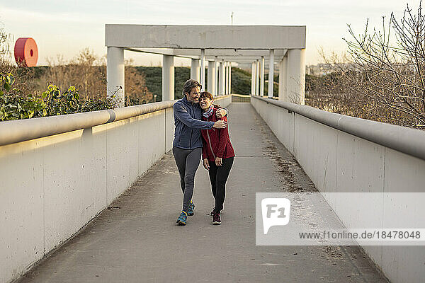 Happy mature man hugging woman on bridge