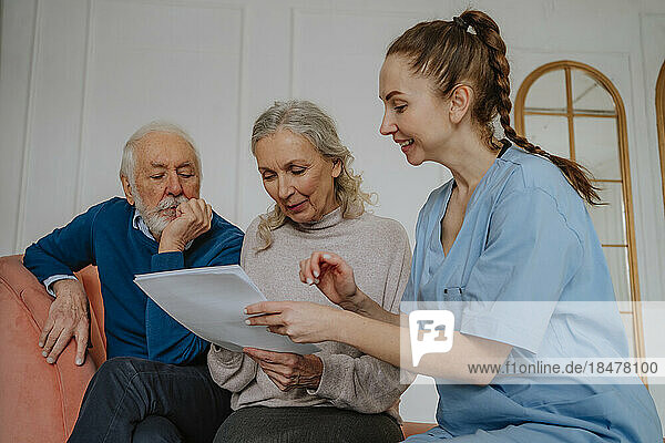 Senior patients reading medical reports by nurse at home