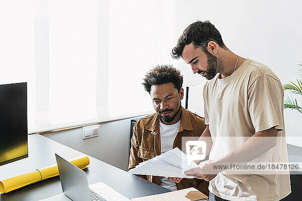 Businessman discussing over documents with colleague at office