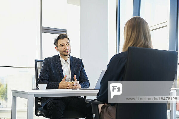 Recruiter discussing with candidate sitting on chair at office