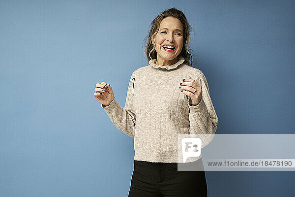 Cheerful woman laughing against blue background