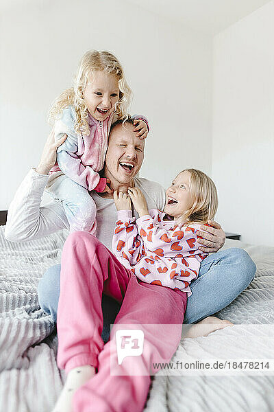 Cheerful father having fun with daughters at home