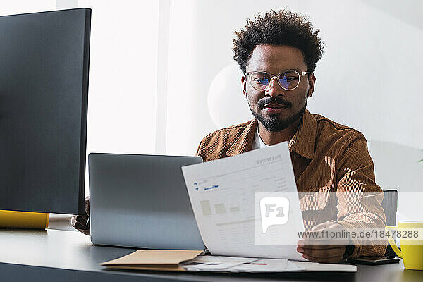 Businessman analyzing document on desk in office