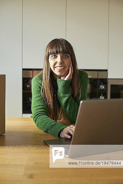 Happy woman with laptop on table at home