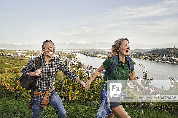 Happy couple holding hands and enjoying hiking on hill
