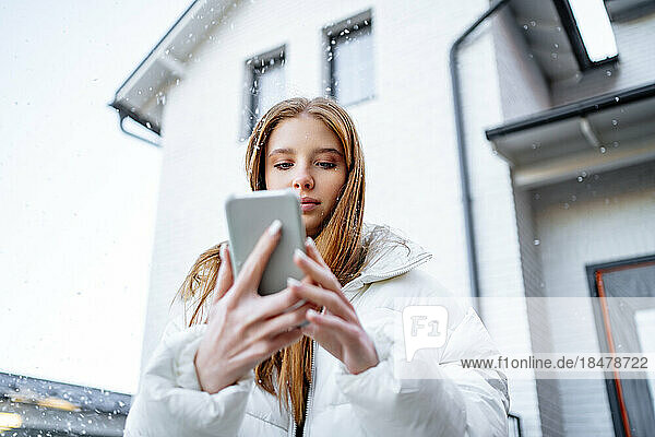 Teenage girl using smart phone outside home