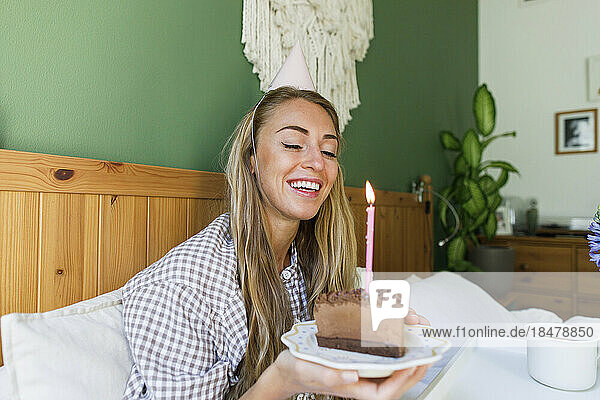 Happy woman with piece of cake enjoying birthday at home