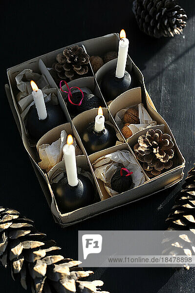 DIY partitioned cardboard box with walnuts  pine cones and burning candles