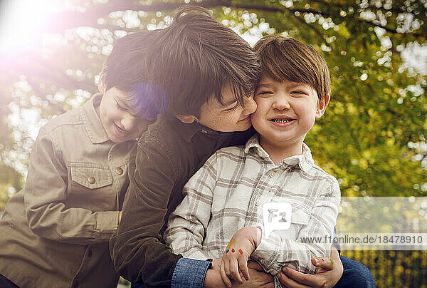 Boy kissing brother at park on sunny day