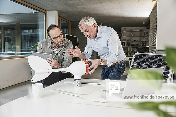 Engineer discussing together over wind turbine rotor at office