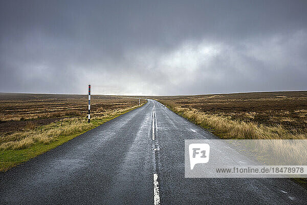 Empty road amidst field under storm clouds  County Durham  England