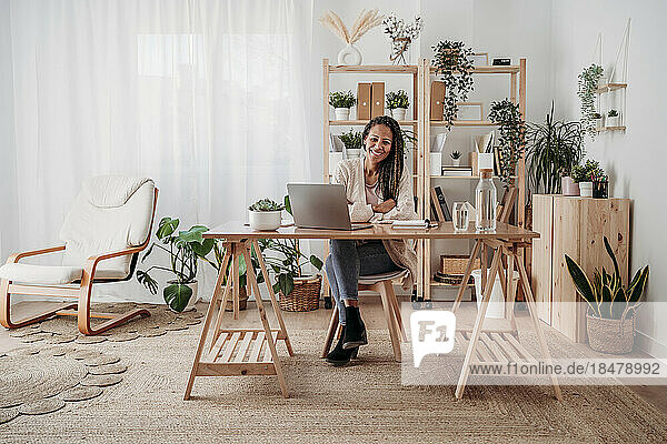 Smiling freelancer sitting at desk in home office