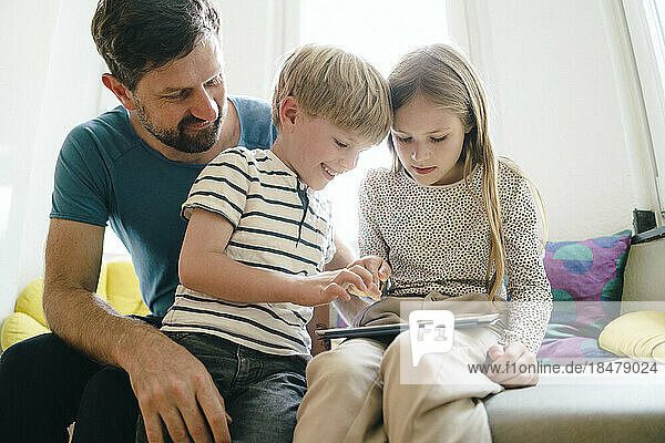 Lächelnder Sohn und Tochter teilen sich zu Hause einen Tablet-PC