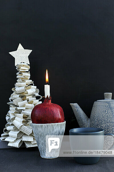 DIY Christmas tree made of book pages and candle burning inside pomegranate