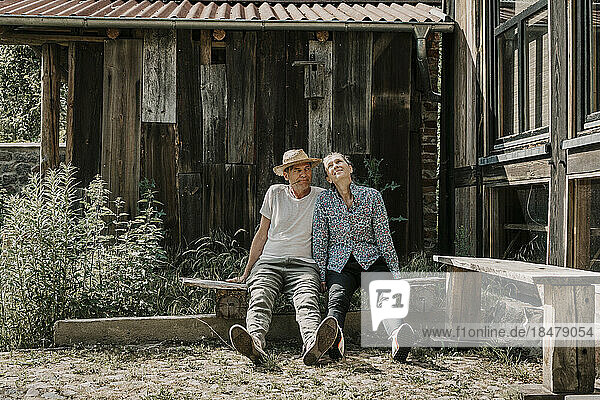 Man and woman sitting together on bench outside barn