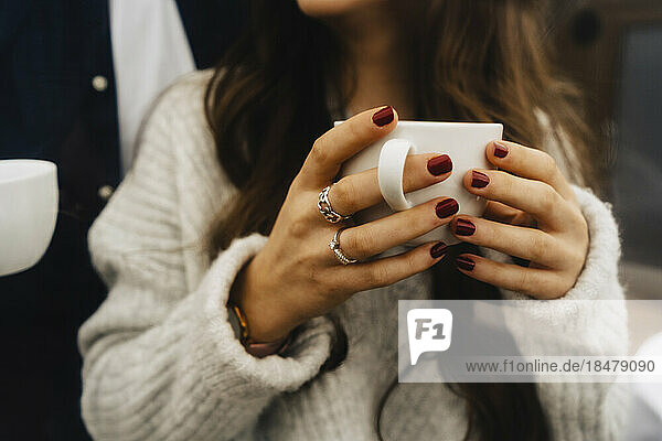 Hände einer Frau mit Kaffeetasse im Kuppelzelt