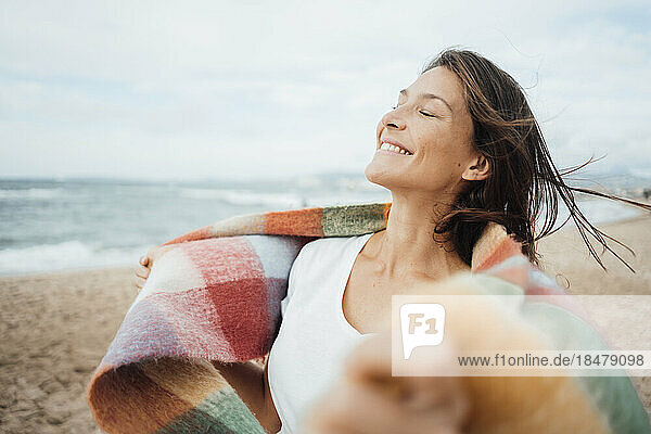Lächelnde Frau mit geschlossenen Augen verbringt ihre Freizeit am Strand