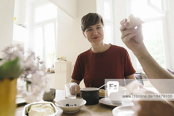 Lächelnde Frau mit Frühstück auf dem heimischen Tisch