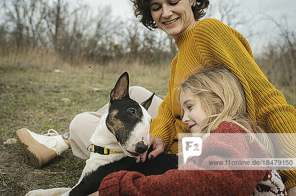 Happy mother and girl sitting with Bull Terrier dog